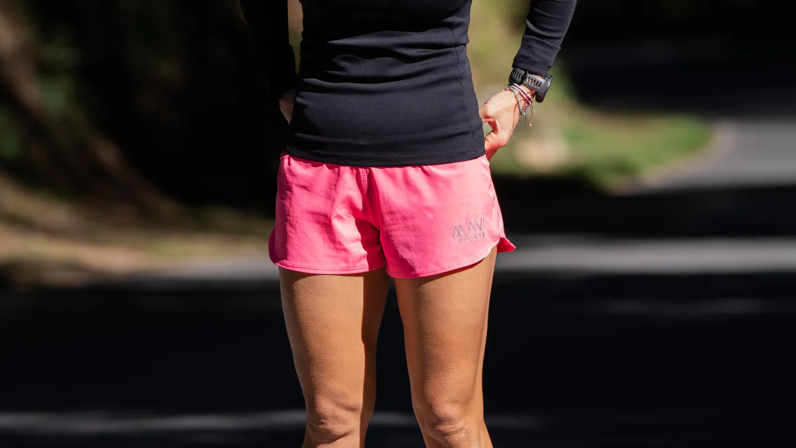 Woman jogging outdoors in pink shorts and a black top