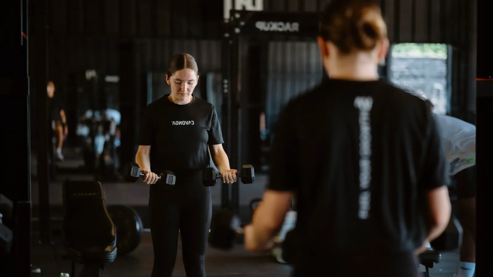Woman lifting dumbbells with focus during a gym strength workout
