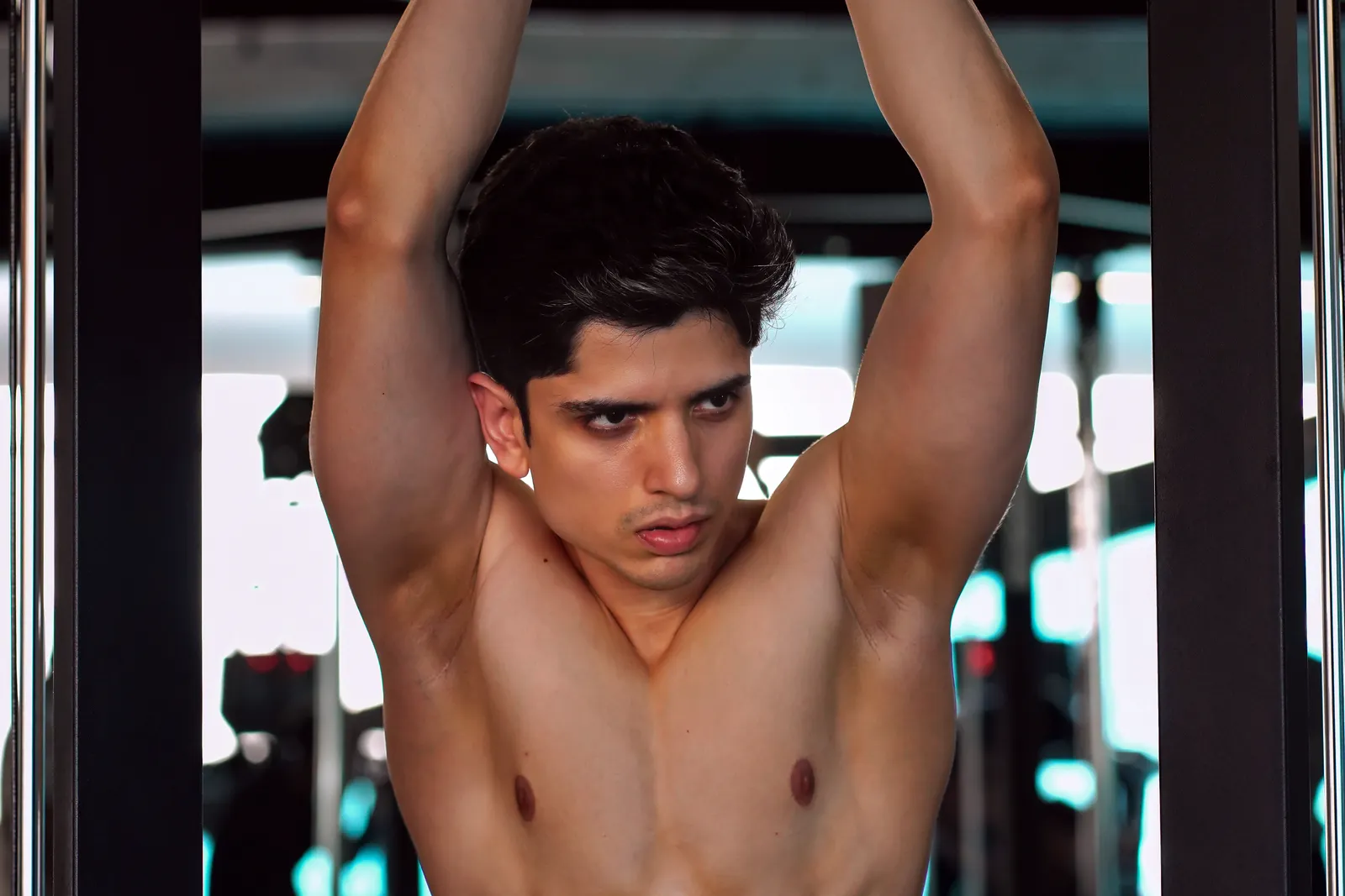 Fit young man doing pull-ups in the gym