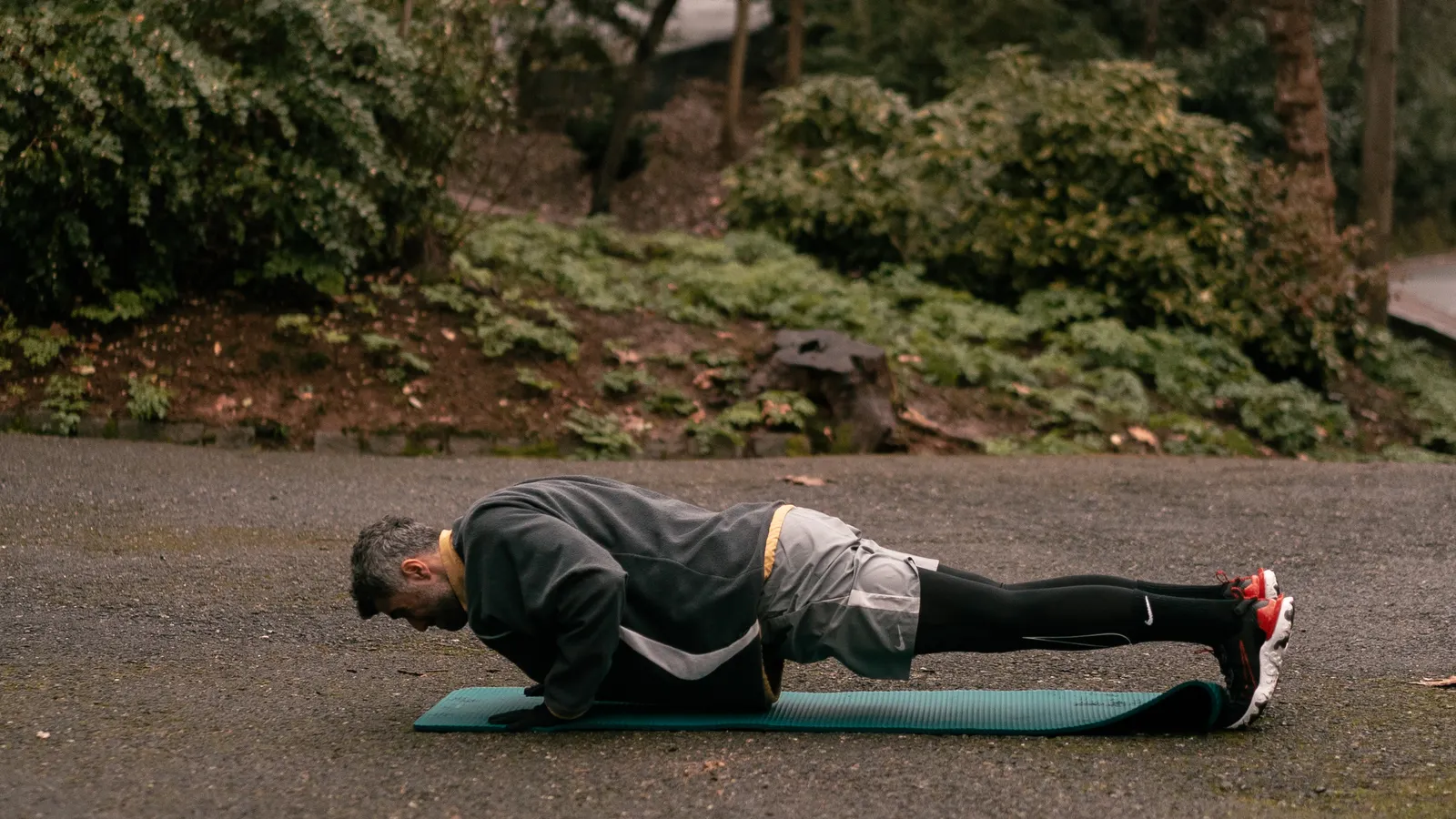 Man exercising on a mat outdoors during a core session